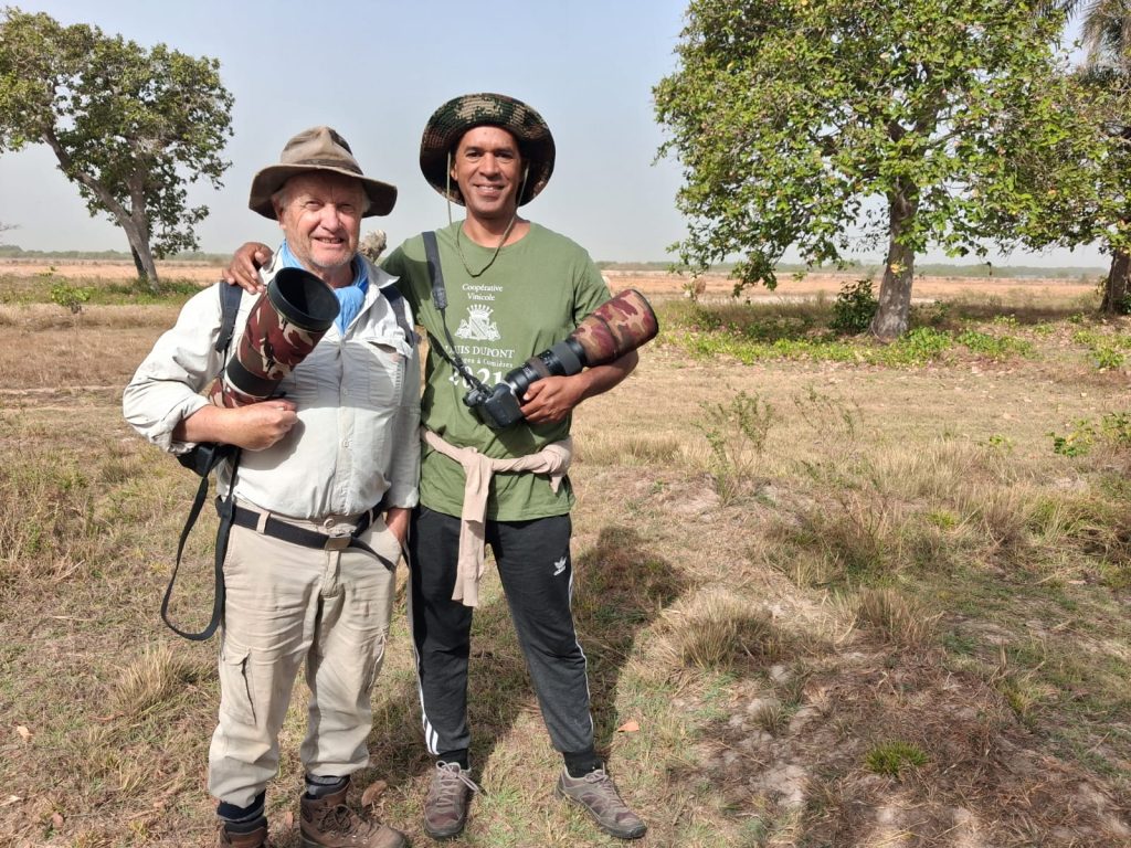 Patrick Tourneur et un ornithologue en sortie terrain — savane de Casamance, appareils longue focale en main.