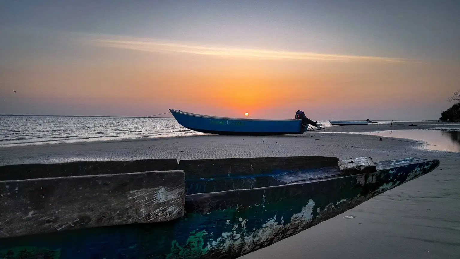 Sunrise over the Casamance river at Pointe Saint-Georges, pirogues beached on the sand